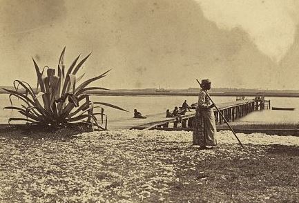 An African American woman works in a field while soldiers lounge on a dock at Seabrook Plantation (detail). LOC.
